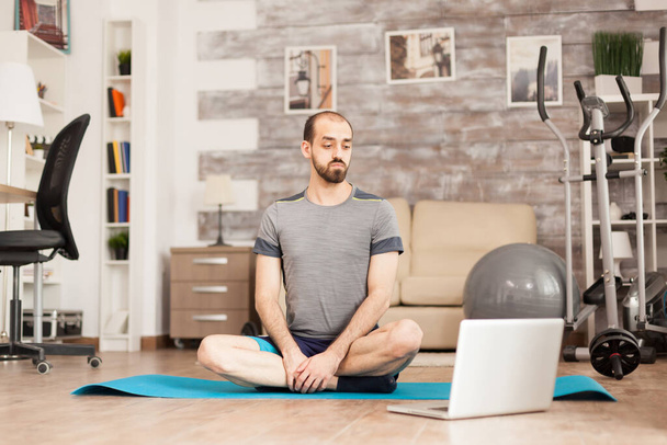 Fit man learning yoga from online course - 写真・画像