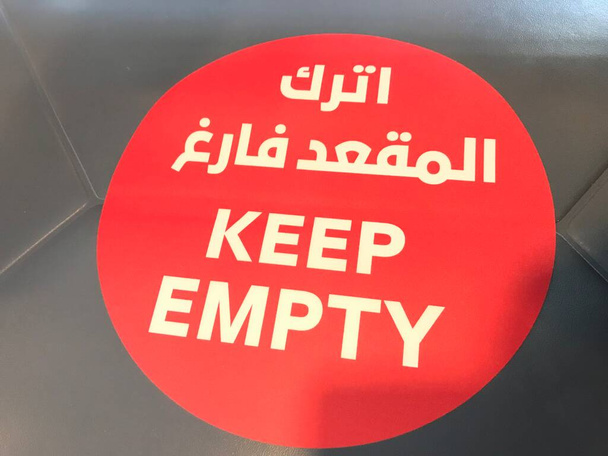 KEEP EMPTY Briefe in weißer Schrift auf rotem Hintergrund in Stühlen geschrieben, um soziale Distanzierung im öffentlichen Bürobereich aufrechtzuerhalten - Foto, Bild