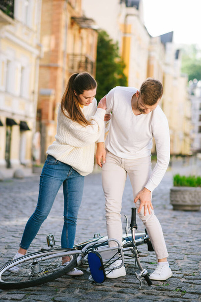 Man with injury and woman standing over bicycle. - Zdjęcie, obraz