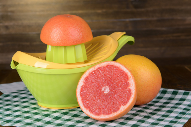Citrus press and grapefruits on table on wooden background - Fotoğraf, Görsel