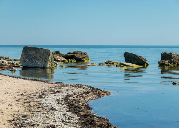 soleado paisaje de verano con una orilla rocosa del mar, restos de una antigua estructura de hormigón en el agua, Isla Saaremaa, Península de Sorves, Estonia
 - Foto, imagen