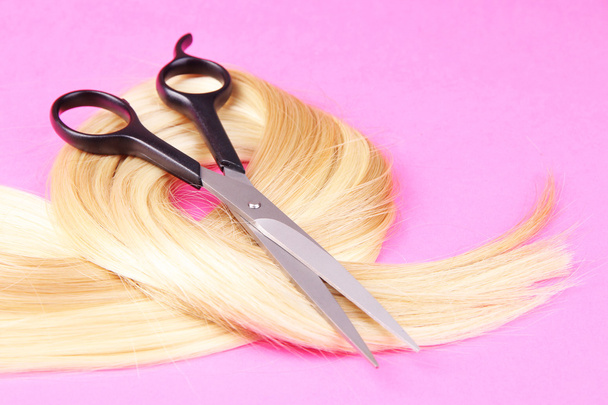 Long blond hair with scissors on pink background - Φωτογραφία, εικόνα