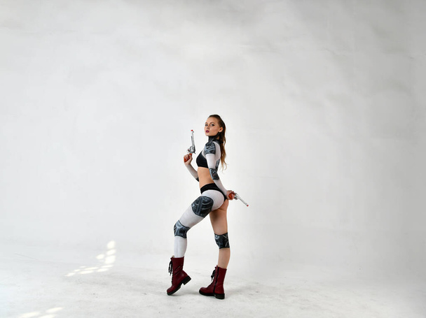 menina bonita em um terno robô faz exercícios para artes marciais com espadas marciais
 - Foto, Imagem
