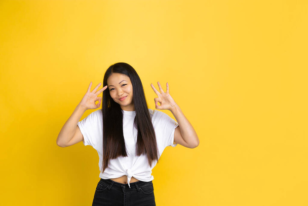 Portrait of young asian woman isolated on yellow studio background - 写真・画像