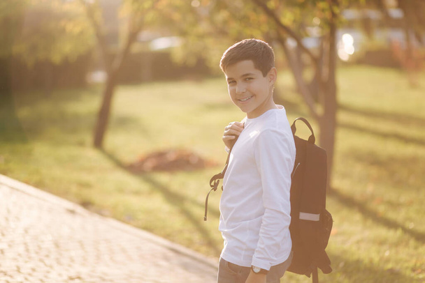 Vista trasera de colegial volver a casa después de las lecciones. Adolescente en camisa blanca vaqueros con mochila
 - Foto, imagen