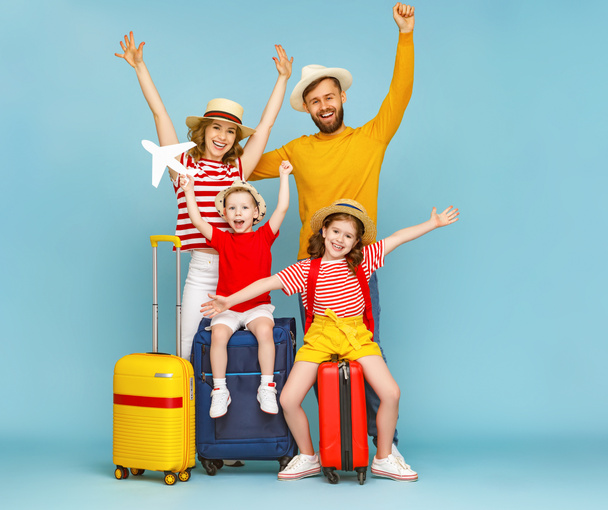 Cuerpo completo feliz familia padres e hijos con los brazos levantados con el equipaje sonriendo se alegran de la próxima viaje de verano contra backdro azul
 - Foto, Imagen
