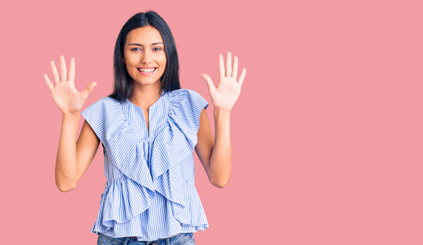 Mladý krásný latinsky dívka na sobě ležérní oblečení ukazuje a ukazuje s prsty číslo deset a zároveň se usmívá sebevědomě a šťastně.  - Fotografie, Obrázek