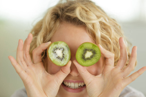 woman with kiwi slices in front of her eyes - Zdjęcie, obraz