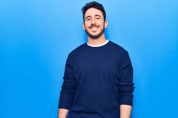 Молодий іспаномовний чоловік в повсякденному одязі виглядає позитивним і щасливим стоячи і посміхаючись з впевненою посмішкою, показуючи зуби
  - Фото, зображення