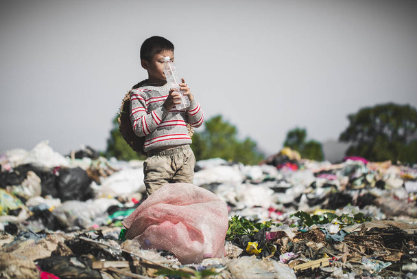 Бедный мальчик собирает мусор с свалки на окраине, жизнь и образ жизни бедных, детский труд, бедность и окружающая среда - Фото, изображение