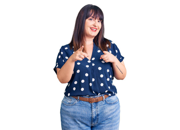 Young plus size woman wearing casual clothes pointing fingers to camera with happy and funny face. good energy and vibes.  - Photo, Image