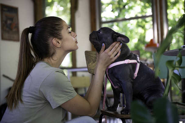Dívka milující a líbání svého psa uvnitř malé zvíře přátelské kavárny - Fotografie, Obrázek