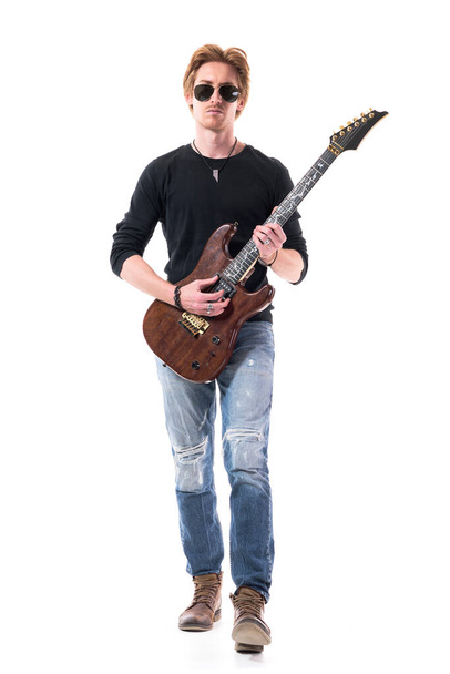 Ein hübscher junger Rocker mit rotem Haar tritt nach vorne und spielt E-Gitarre. Ganzes Porträt isoliert auf weißem Hintergrund.  - Foto, Bild