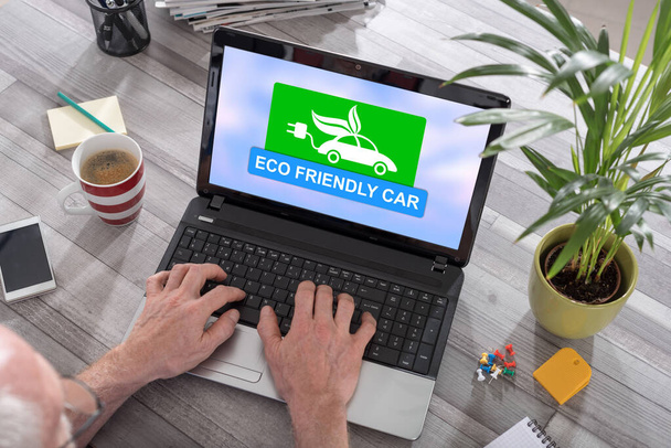 Homem usando um laptop com conceito de carro eco amigável na tela
 - Foto, Imagem