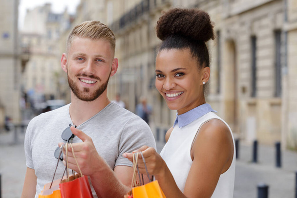 portrait of young couple in city showing their shopping bags - Photo, Image