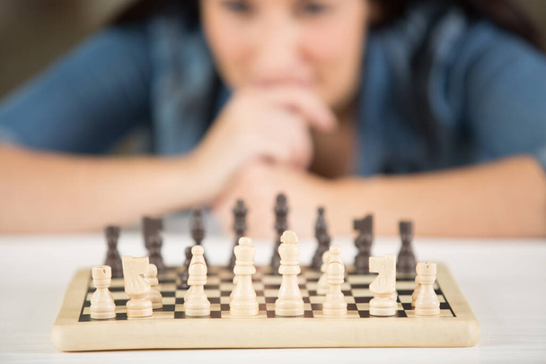 a woman is playing chess alone - Foto, Imagen
