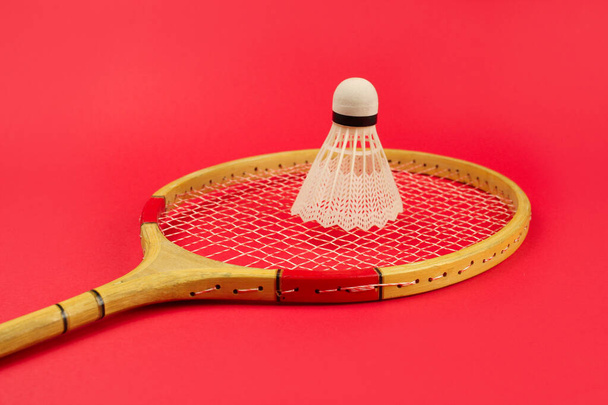 Shuttlecock op een badminton racket op een heldere rode achtergrond - Foto, afbeelding