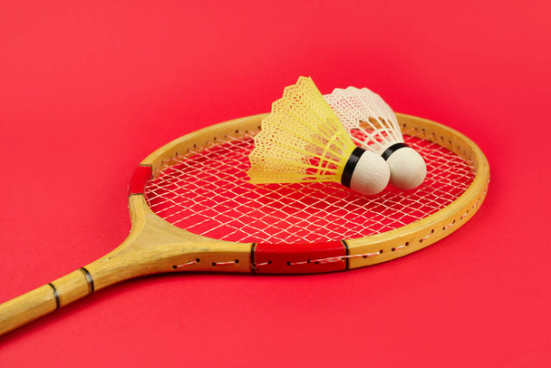 Shuttlecock op een badminton racket op een heldere rode achtergrond - Foto, afbeelding