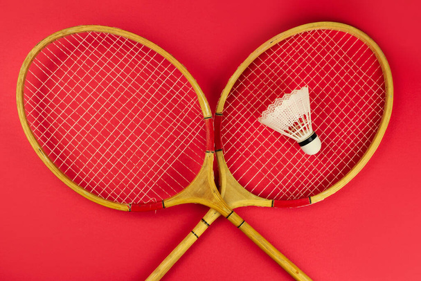 badminton rackets and shuttlecock on a bright red background - Фото, изображение