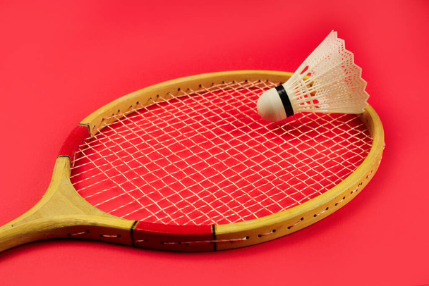 Shuttlecock en una raqueta de bádminton sobre un fondo rojo brillante
 - Foto, imagen
