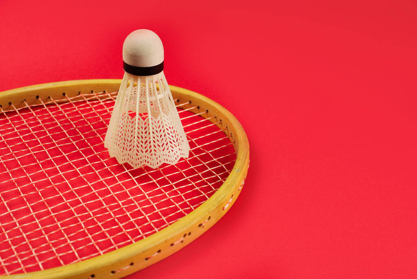 Shuttlecock, parlak kırmızı arka planda badminton raketinde - Fotoğraf, Görsel