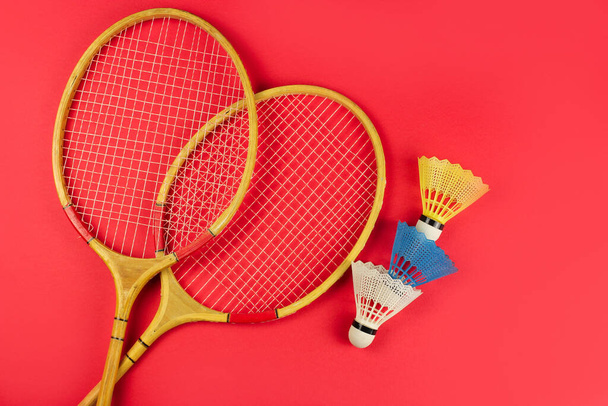 badminton rackets and shuttlecock on a bright red background - Fotó, kép