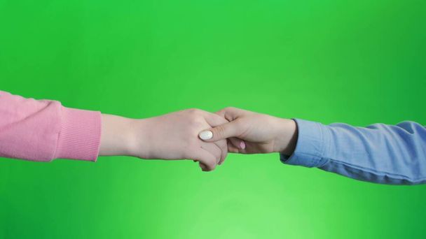 Barátok kezet ráznak. Kézfogás két kézzel, karikás zöld vászon - Fotó, kép