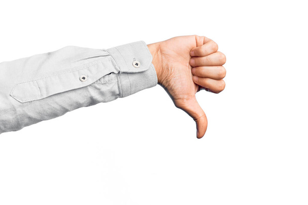 Mano de joven caucásico mostrando dedos sobre fondo blanco aislado haciendo pulgares hacia abajo gesto de rechazo, desaprobación aversión y signo negativo - Foto, Imagen