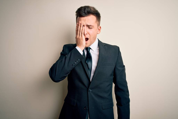 Young handsome business man wearing elegant suit and tie over isolated background Yawning tired covering half face, eye and mouth with hand. Face hurts in pain. - Photo, Image