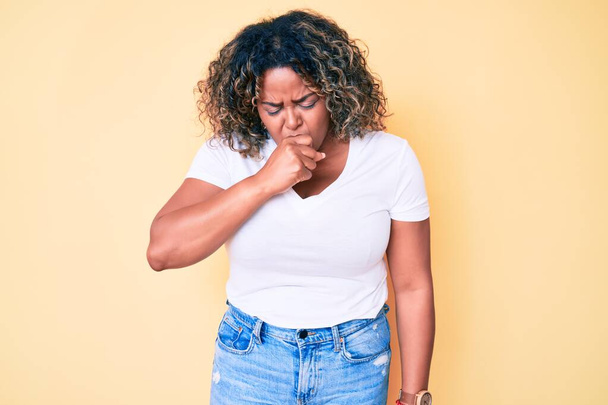 Młoda Afroamerykanka plus size kobieta nosząca luźną białą koszulę źle się czuje i kaszle jako objaw przeziębienia lub zapalenia oskrzeli. koncepcja opieki zdrowotnej.  - Zdjęcie, obraz