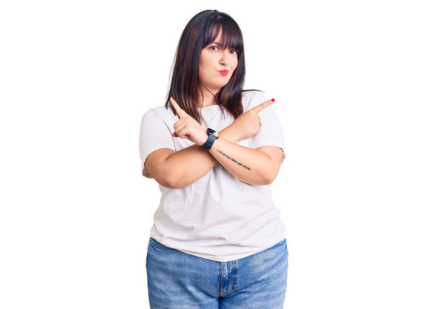 Young plus size woman wearing casual clothes pointing to both sides with fingers, different direction disagree  - Fotó, kép