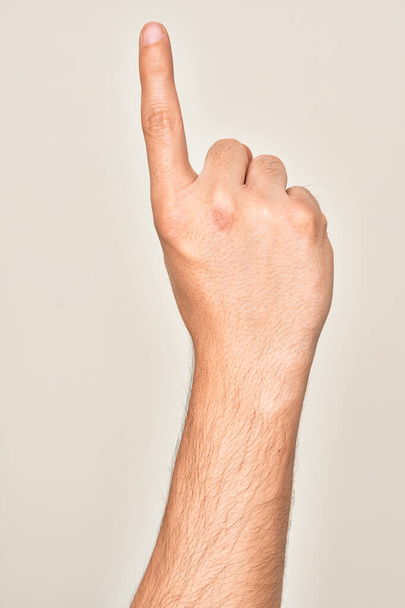Рука кавказского юноши показывает пальцами на изолированном белом фоне, подсчитывая номер один указательным пальцем, показывая идею и понимание - Фото, изображение