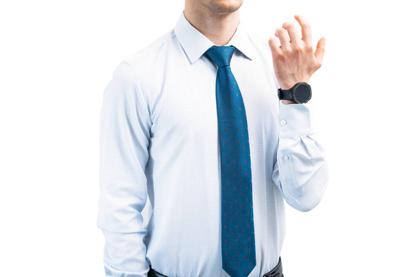 Un gars en chemise légère avec une cravate sur un fond blanc leva la main avec une montre intelligente. - Photo, image