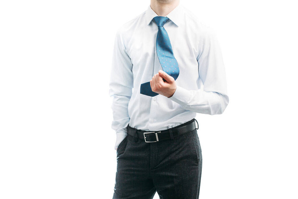 A guy in a white shirt holds himself by a blue tie. A guy takes off his tie. Businessman. Manager - Фото, изображение