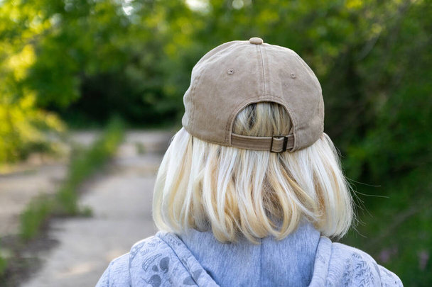 Вид ззаду блондинки в бейсбольній шапці на вулиці
 - Фото, зображення