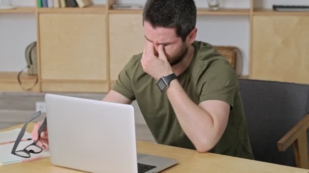 A tired young man is touching his closed eyes during work with his laptop - Кадри, відео