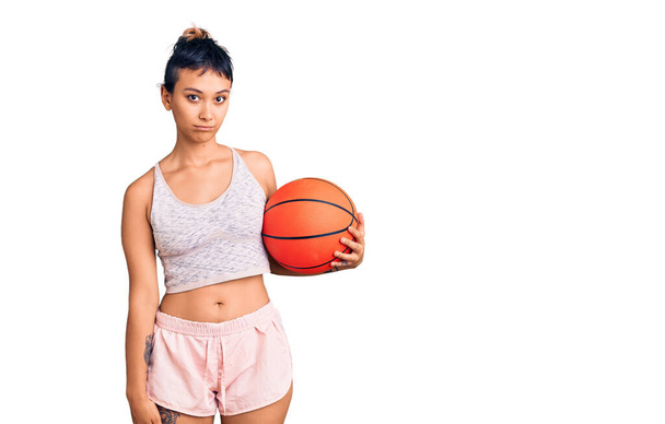 Fiatal nő kezében kosárlabda gondolkodás hozzáállás és józan kifejezés keres magabiztos  - Fotó, kép