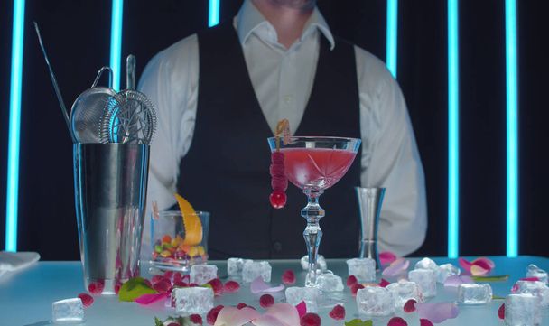 Close up gkass of ready-made Red Dress cocktail on the table in a bar. Long drink decorated with raspberries on a skewer - Fotó, kép