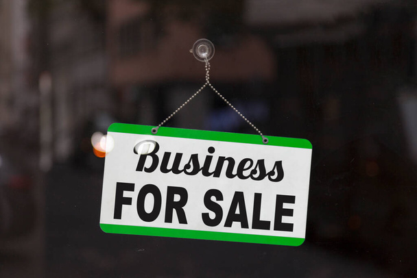 Primo piano su un cartello blu aperto nella finestra di un negozio che mostra il messaggio: Business in vendita - Foto, immagini
