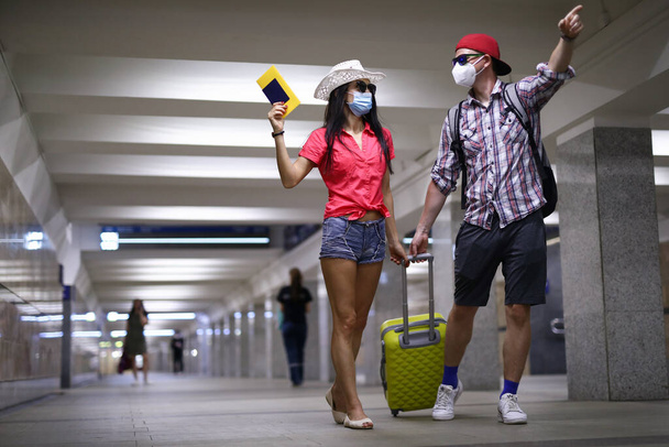 Счастливая пара в защитной медицинской маске пройти туннель на терминале аэропорта и держать паспорт в руке портрет - Фото, изображение