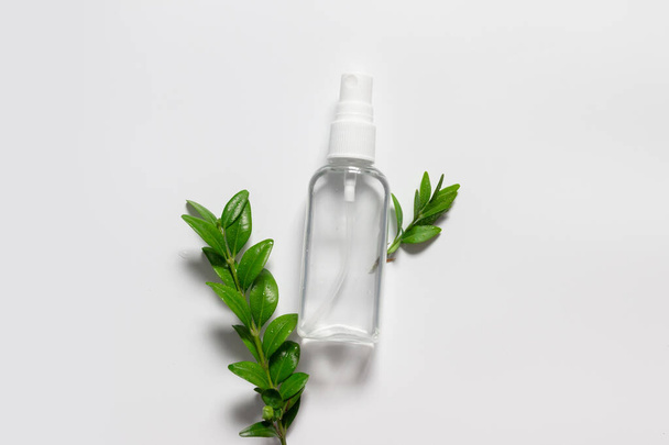 Natural cosmetic plastic bottle with liquid and green leaves on grey background. - Valokuva, kuva
