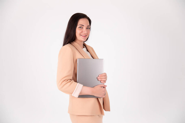 Femme d'affaires réussie sur fond gris avec espace de copie. Réalisateur en costume strict avec ordinateur portable - Photo, image