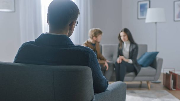 Unfocused Couple on Counseling Session with Psychotherapist. Focus on Back of Therapist Taking Notes and Talking: People Sitting on Analyst Couch, Discussing Psychological and Relationship Problems - Фото, зображення
