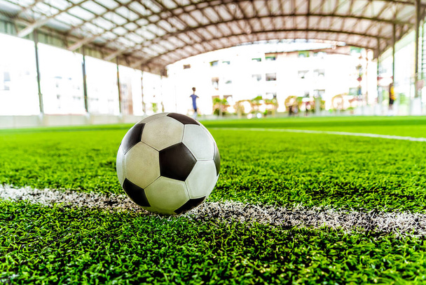 Используется выветренный классический черно-белый футбольный мяч на тренировочном поле с размытым фоном - Фото, изображение