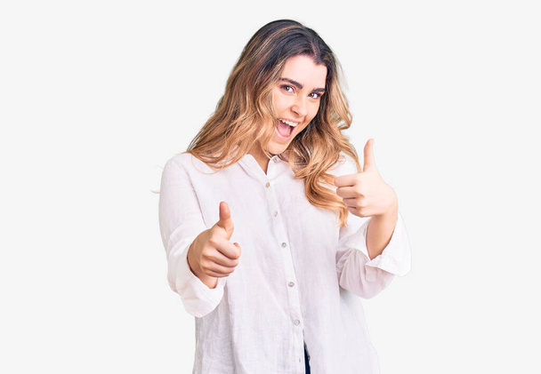 Young caucasian woman wearing casual clothes success sign doing positive gesture with hand, thumbs up smiling and happy. cheerful expression and winner gesture.  - Foto, Imagem