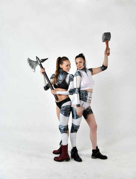 dos hermosas chicas en trajes de robots como niños luchan contra las armas militares
 - Foto, Imagen
