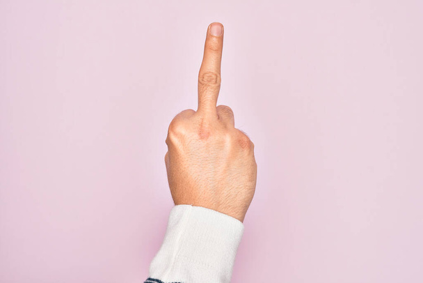 Рука кавказского юноши показывает пальцы на изолированном розовом фоне показывая провокационный и грубый жест делает трахнуть вас символ средним пальцем
 - Фото, изображение