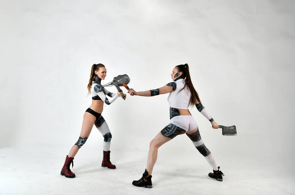 two beautiful girls in costumes of robots as children fight military weapons - Photo, Image