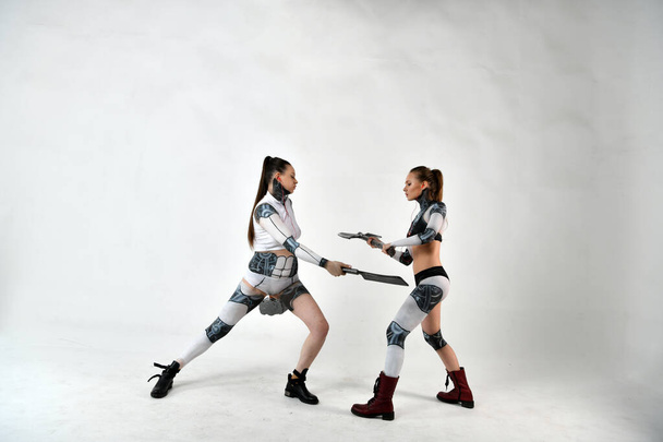 two beautiful girls in costumes of robots as children fight military weapons - Фото, зображення