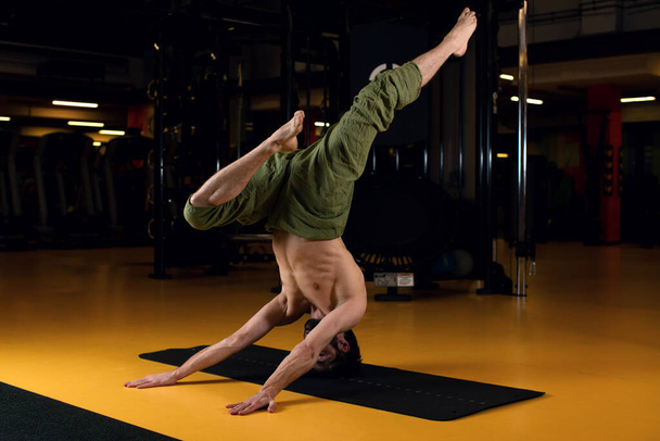 Yoga man in studio performs a complex element of yoga is Shirshasan - Photo, image